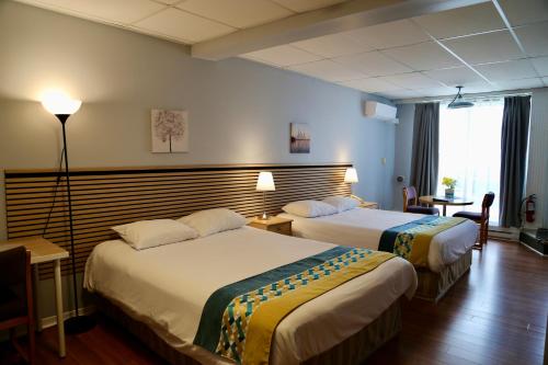 a hotel room with two beds and a lamp at Motel Bel-Eau in Montebello