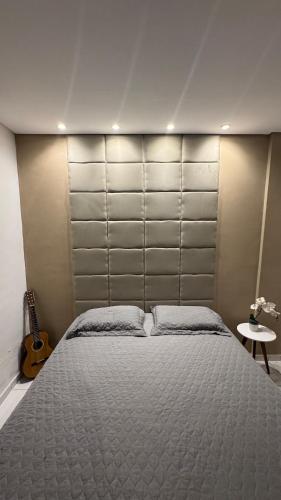 a bedroom with a large bed and a guitar at 1- Apartamento aconchegante 1200m do Centro in Serra Talhada