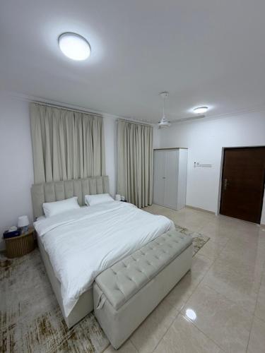 a bedroom with a large white bed and a couch at جوهرة الخوض in Al Khawḑ