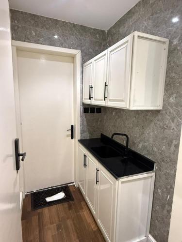 a kitchen with white cabinets and a black sink at استوديو حي حطين in Riyadh