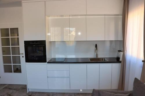 a kitchen with white cabinets and a sink at Apartmani Jozić 2 in Ripci