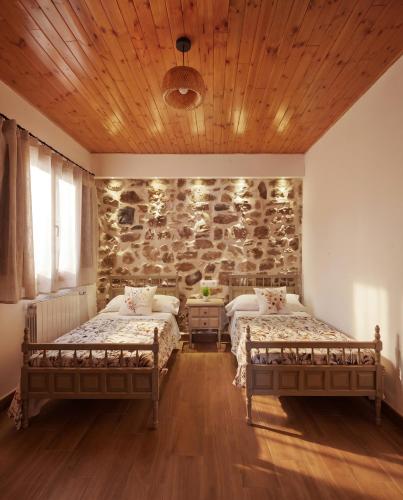 two beds in a room with a stone wall at Ca la Inés in Corbera