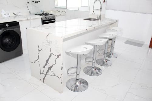 a white kitchen with marble counter tops and stools at Apartment in Ancon in Ancón