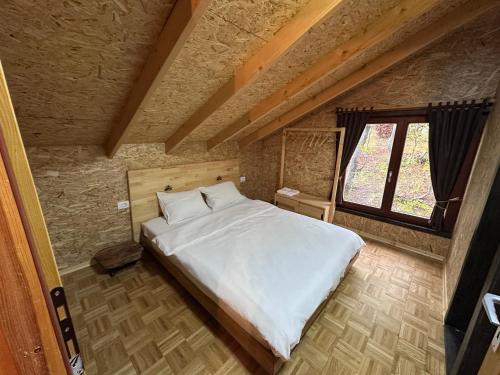 a bedroom with a large white bed with a window at Stanetestruzhes in Prizren