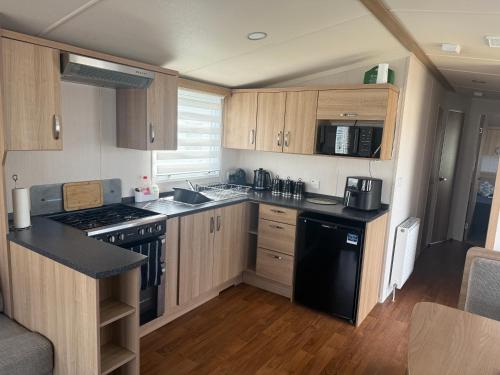 a kitchen with wooden cabinets and a black appliances at CJ Coastal Getaway #2 in Rhyl