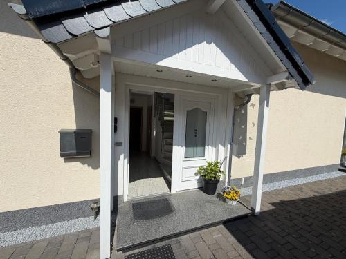 ein weißer Eingang zu einem Haus mit einer Tür in der Unterkunft Ferienwohnung Balkon oder Terrasse in Kall