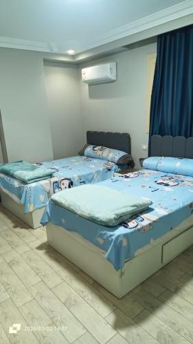 two twin beds in a room with blue sheets at Ashraf Residential Complex in Luxor