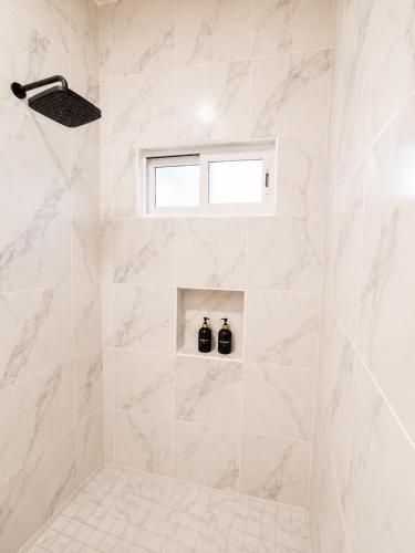 a white bathroom with a shower with two bottles at Cabo Downtown Studios in Cabo San Lucas