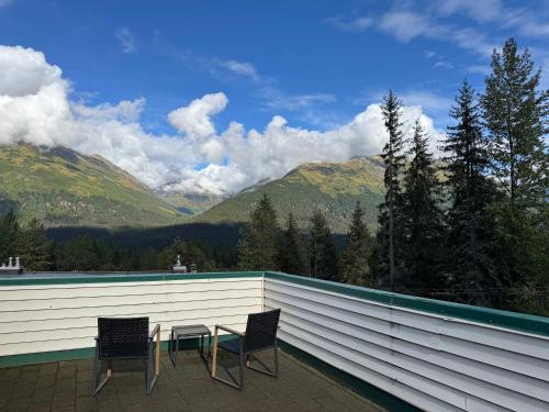 two chairs and a table on a balcony with mountains at Alpine Charm By Alyeska Sleeps 6 in Girdwood