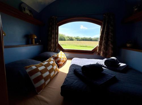 a room with two beds and a window with a view at La roulotte CIRCUS des Grillots in Beaulon