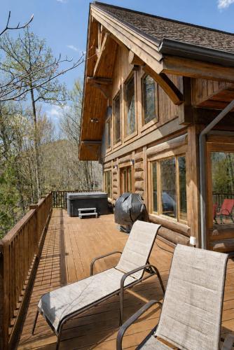 a deck with chairs and a grill on a log cabin at Belvedere sur le Lac Lodge in Sainte-Adèle