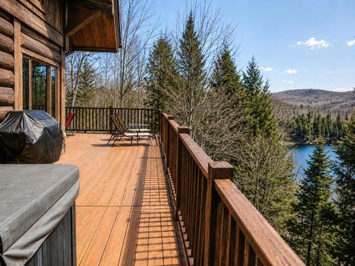 a wooden balcony of a cabin with a view of a lake at Belvedere sur le Lac Lodge in Sainte-Adèle