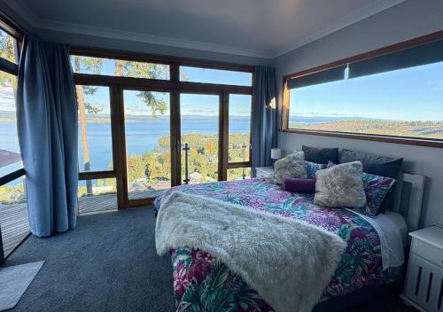 a bedroom with a bed with a view of the ocean at The Nest - Guest House, Acacia Bay, Panoramic Lake Views in Taupo