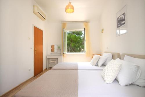 a white bedroom with two beds and a window at Apartments Katušić in Cavtat
