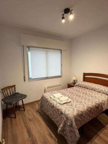 a bedroom with a bed and a chair and a window at Recuncho de Corme, a 100 metros de la playa in Corme-Puerto