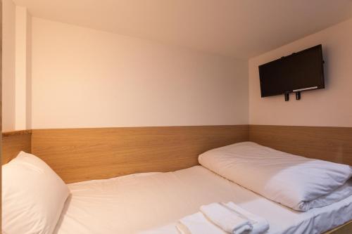 a room with two beds with a flat screen tv on the wall at HOTEL THE CUBE Naha Kokusai Street in Naha