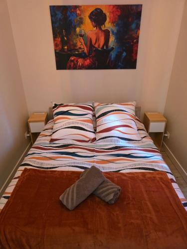 a bed in a room with a painting on the wall at L'Escapade Chablisienne in Chablis