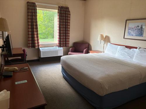 a hotel room with a bed and a chair at Magnason Hotel in West Liberty