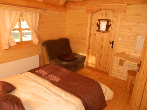 a bedroom with a bed and a chair in a cabin at Glamping Organic Farm Slibar in Tržič
