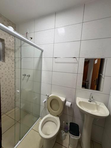 a bathroom with a shower and a toilet and a sink at Pousada Nascer da Lua in São Thomé das Letras