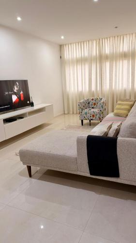 a bedroom with a bed and a tv and a chair at 3 Ls APARTAMENTO in Luanda