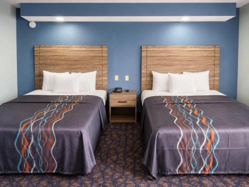 two beds in a hotel room with blue walls at Travelodge by Wyndham Barstow in Barstow