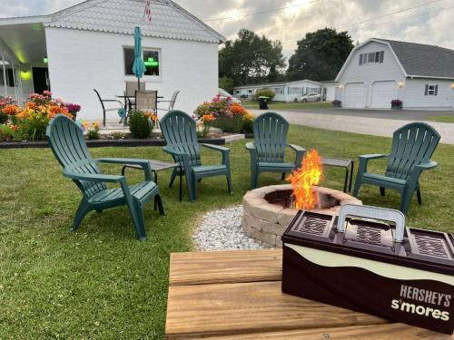 a fire pit with four chairs and a table at Cedars Motel in Saint Ignace