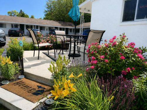 a garden with flowers and a table and chairs at Cedars Motel in Saint Ignace