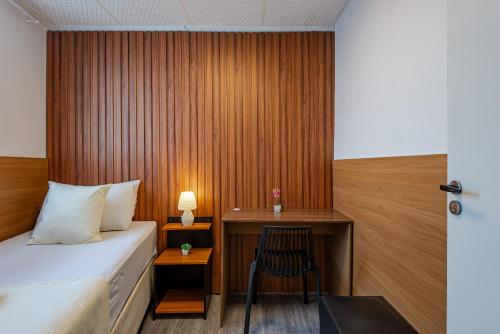 a bedroom with a bed and a desk with a chair at Pousada Hostheo liberdade in São Paulo