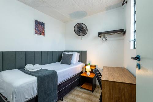 a small room with a bed and a desk with a lamp at Pousada Hostheo liberdade in São Paulo