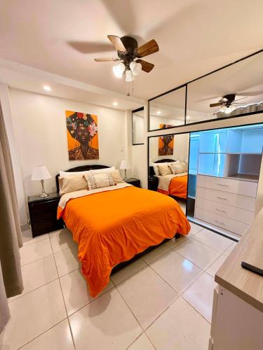 a bedroom with an orange bed and a ceiling fan at Departmento Grande in Puerto Chicama