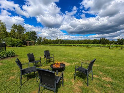 a group of chairs around a fire pit in a field at Stay at Shiraz in Pokolbin