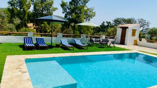 a swimming pool with chairs and umbrellas and a table at Casa La Rocita in Badajoz