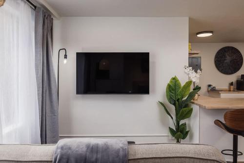 a living room with a couch and a tv on a wall at Stylish Downtown Studio - Free Parking plus Kitchen in Anchorage