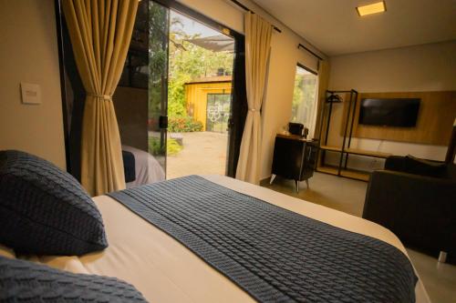 a bedroom with a bed and a sliding glass door at Hotel Flores de Holambra in Holambra