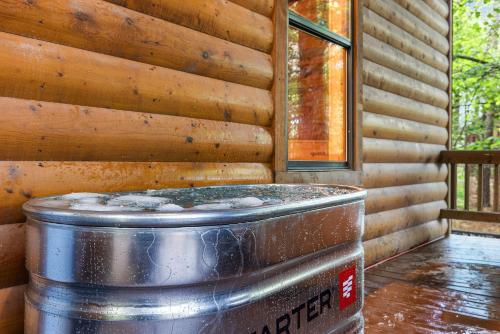 a large metal tub sitting next to a wooden wall at Luxury Cabin Near Lake - Sauna, Cold Plunge, Hot Tub, Fire Pit, & Games in Broken Bow