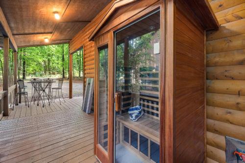 a screened in porch with a glass door on a wooden house at Luxury Cabin Near Lake - Sauna, Cold Plunge, Hot Tub, Fire Pit, & Games in Broken Bow