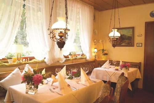 uma sala de jantar com duas mesas com toalha de mesa branca em Landhaus Meyer em Riefensbeek