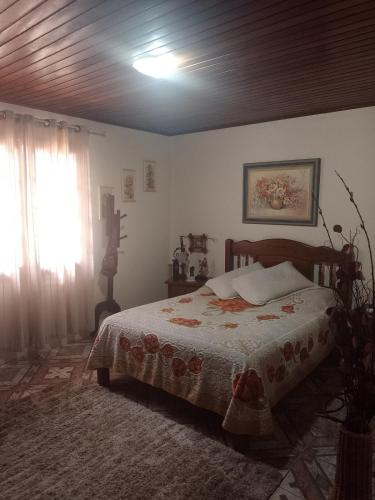 a bedroom with a bed and a window and a ceiling at Aconchego da Wal in Campos do Jordão