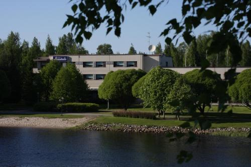 a building with a lake in front of a building at Hotelli Puustelli Lieksa in Lieksa