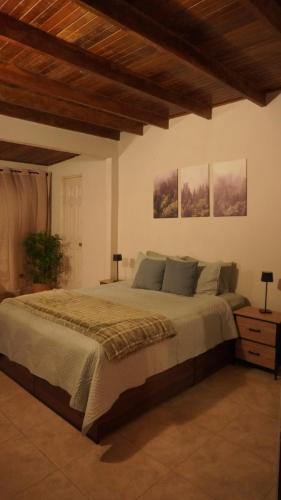 a bedroom with a large bed and two pictures on the wall at Windwood Cabin Cerro Azul in Los Altos de Cerro Azul