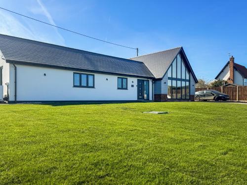 a white house with a green lawn in front of it at Seafields in Sidestrand