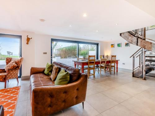 a living room with a leather couch and a dining room at Ty Eufron in St. Davids