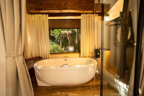 a white bath tub in a bathroom with a window at Hotel Flores de Holambra in Holambra