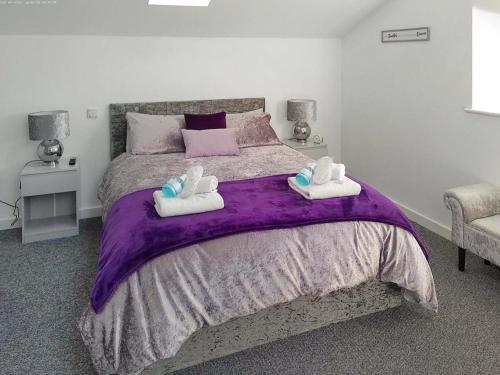 a bedroom with a large bed with purple sheets and towels at Red Kite Cottage-Ukc6982 in Consett