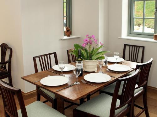 a wooden table with plates and wine glasses on it at Kites Gate Cottage in Kingham