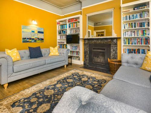 a living room with two couches and a fireplace at Plas Bodegroes in Pwllheli
