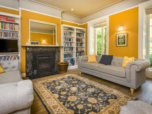 a living room with two couches and a fireplace at Plas Bodegroes in Pwllheli