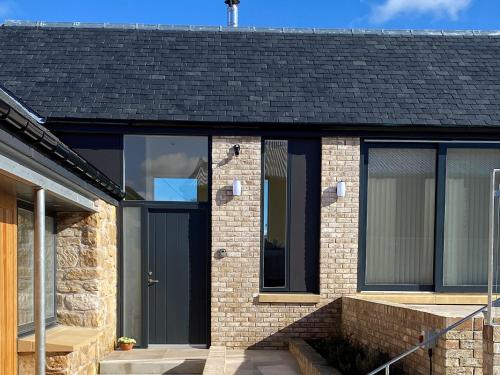 a brick house with a black door and windows at Falcon Cottage in Linlithgow