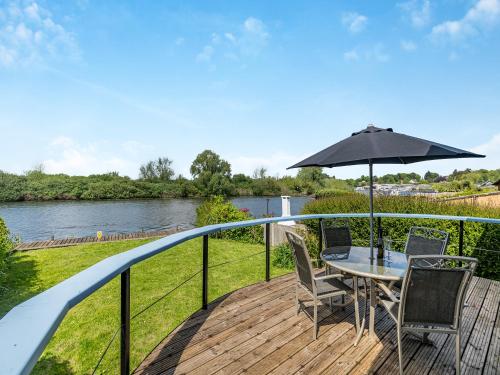 a deck with a table and chairs and an umbrella at River View-Ukc6112 in Brundall